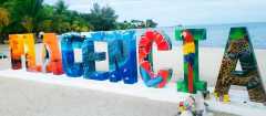 Welcome to Placencia. This sign, located on the beach in the Village with Chabil Mar Resort and Pier in the background.