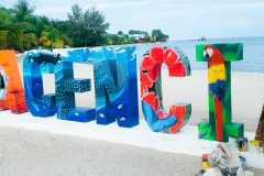 Welcome to Placencia. This sign, located on the beach in the Village with Chabil Mar Resort and Pier in the background.